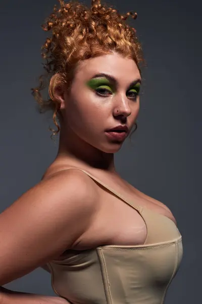 Portrait of self-confident redhead woman with curvy body and bold makeup on dark grey backdrop — Stock Photo