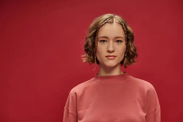 Ritratto di giovane bella donna con capelli corti ondulati e trecce guardando la fotocamera su sfondo rosso — Foto stock