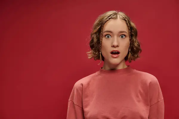 Porträt einer jungen und schockierten Frau mit kurzen welligen Haaren und Zöpfen auf rotem Hintergrund, Überraschung — Stockfoto