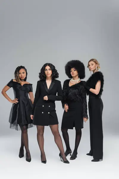 Gruppe eleganter, multiethnischer Frauen in ganz schwarzer Kleidung, die auf grauen, modischen Freundinnen stehen — Stockfoto