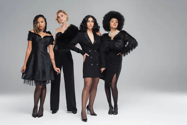 Comprimento total de modelos femininos multirraciais em traje preto posando em pano de fundo cinza, beleza diversificada — Fotografia de Stock