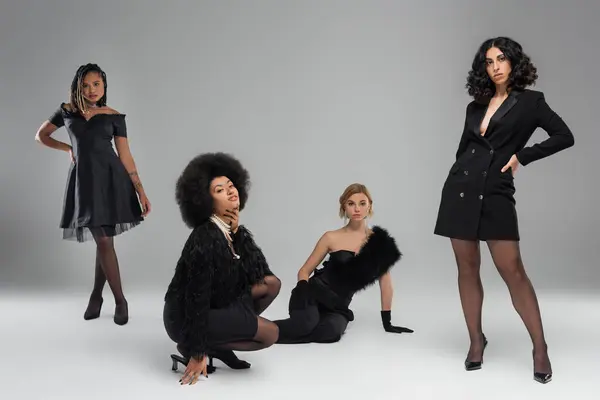 Vielfältige Mode, multiethnische Freundinnen in schwarzen trendigen Outfits posieren vor grauem Hintergrund im Studio — Stockfoto