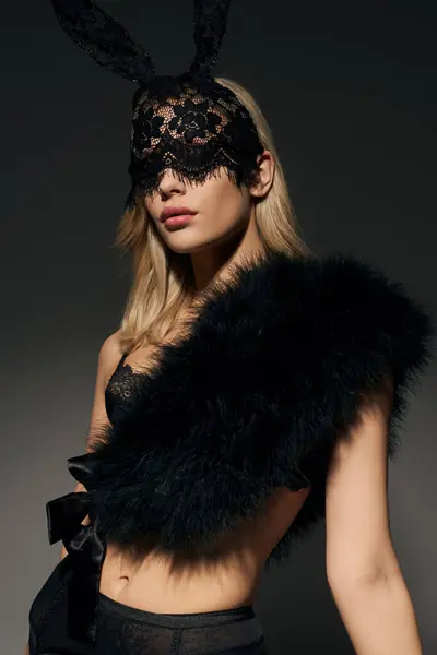 Tiro vertical de mujer sexy en lencería de encaje negro y piel sintética con máscara de conejo mirando a la cámara - foto de stock