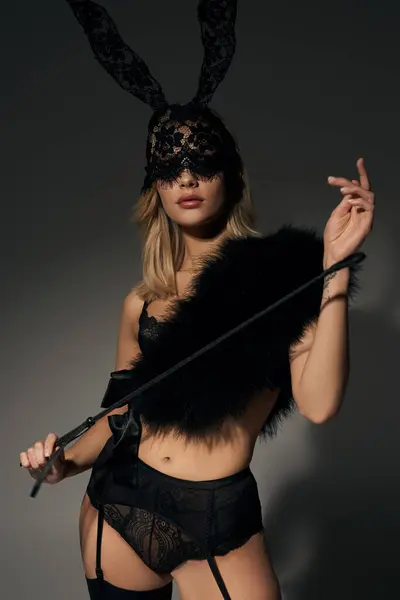 Vertikale Aufnahme einer heißen Frau in sexy Spitzenunterwäsche mit Kaninchenmaske und Kunstpelz mit BDSM-Peitsche — Stockfoto