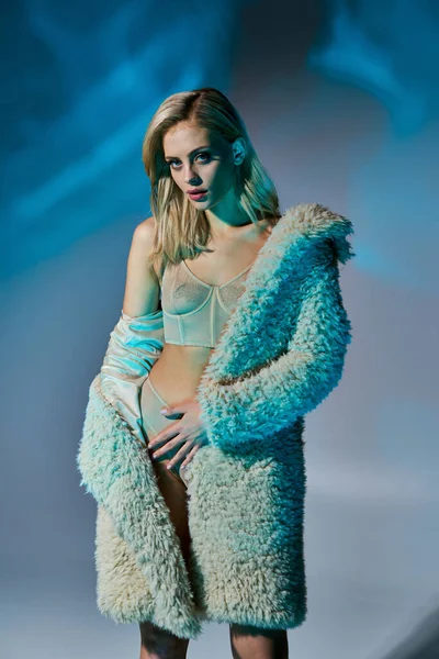Colpo verticale di donna seducente con i capelli biondi in posa in abbigliamento sexy circondato da luci blu — Foto stock