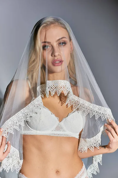 Portrait of alluring blonde woman in sexy white lace underwear and veil looking lovingly at camera — Stock Photo