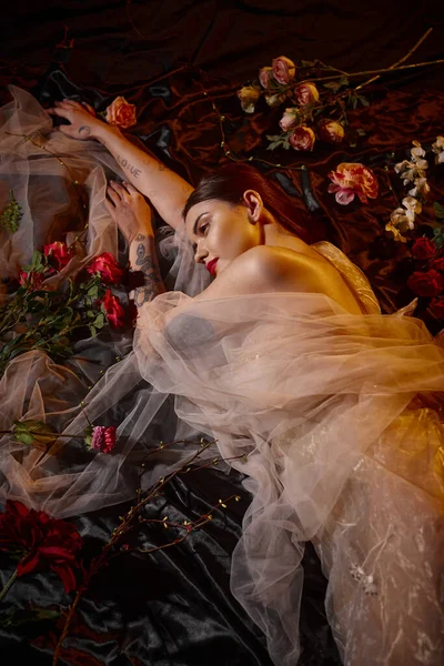 Charmante sinnliche junge Frau in romantischem transparentem Kleid zwischen blühenden Blumen liegend, Draufsicht — Stockfoto