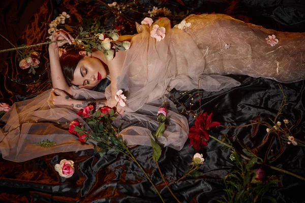Attraktive und sinnliche junge Frau in romantischem transparentem Kleid zwischen blühenden Blumen liegend — Stockfoto