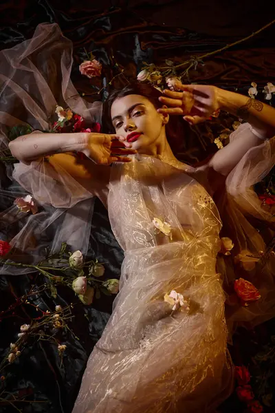 Feminine elegance, sensual young woman in transparent dress lying among beautiful flowers, top view — Stock Photo