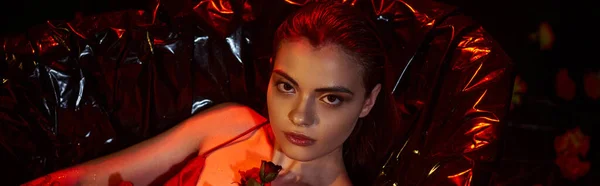Attractive young woman in wet slip dress lying in black bathtub with blooming flowers, banner — Stock Photo