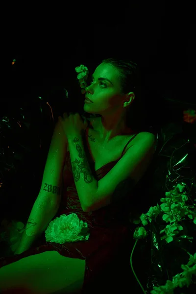 Green light, sensual and elegant woman with wet hair looking away and posing among flowers — Stock Photo
