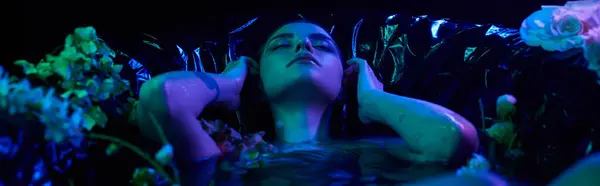Bannière de lumière bleue, sensuelle et jeune femme avec les cheveux mouillés plongeant dans l'eau dans la baignoire avec des fleurs — Photo de stock