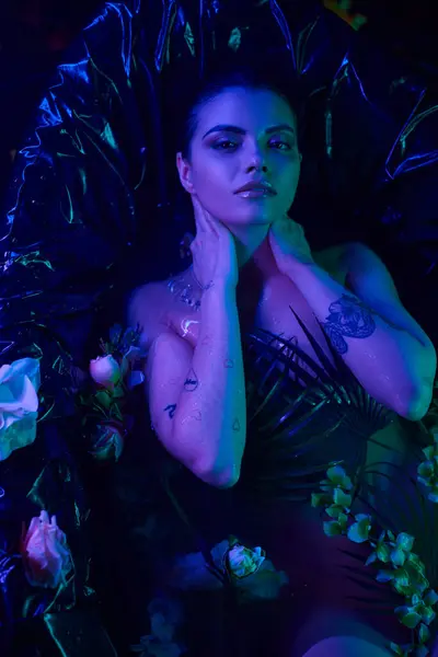 Azul claro, atractiva y joven mujer con el pelo mojado buceando en el agua en la bañera con flores - foto de stock