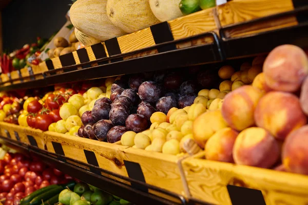 Foto de colorido puesto de frutas con melocotones, ciruelas y melones en la tienda de comestibles, nadie, foto del objeto - foto de stock