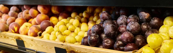 Foto del objeto del puesto vibrante de la tienda de comestibles con ciruelas frescas deliciosas, limones y melocotones, bandera - foto de stock