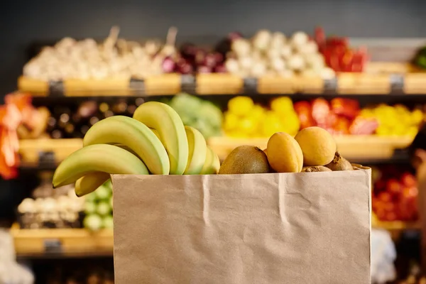 Objektfoto einer Einkaufstasche voller frischer, natürlicher Früchte mit verschwommenem Lebensmittelstand vor dem Hintergrund — Stockfoto