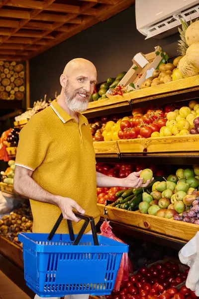 Fröhliche, graubärtige männliche Kundin pflückt frisches Obst und lächelt im Supermarkt in die Kamera — Stockfoto