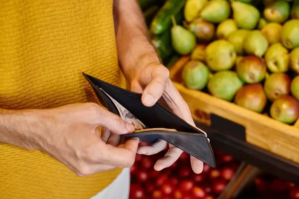 Vista recortada de un cliente varón maduro sosteniendo su billetera en manos listas para pagar en la tienda de comestibles - foto de stock