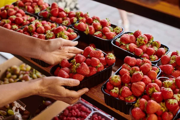 Abgeschnittene Ansicht von reifen Verkäufer hält Packung mit frischen nahrhaften lebendigen Erdbeeren im Lebensmittelgeschäft — Stockfoto