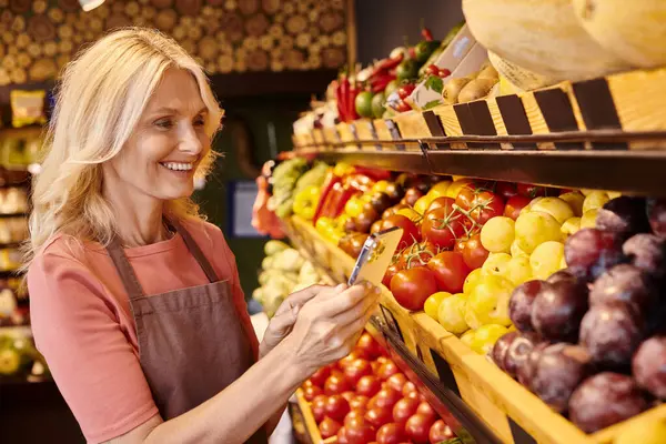 Gioioso attraente venditore maturo scattare foto sul telefono di frutta e verdura fresca vibrante — Foto stock