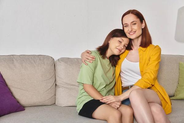 Smiling woman embracing happy teenage daughter on sofa in modern living room, happy relationship — Stock Photo