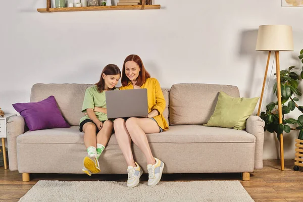 Happy woman with teenage daughter watching movie on laptop on couch in living room, quality time — Stock Photo