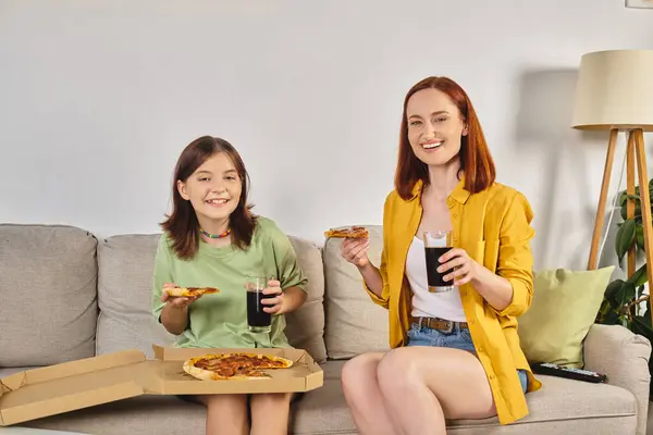 Cheerful mother and teenage daughter with pizza and soda on cozy couch in living room, pizza time — Stock Photo