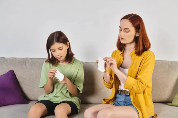 Mother showing sanitary pads to teenage daughter during sex education talk at home, feminine care — Stock Photo