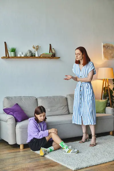 Donna seria che parla con frustrata figlia adolescente seduta sul pavimento in soggiorno, divario generazionale — Foto stock