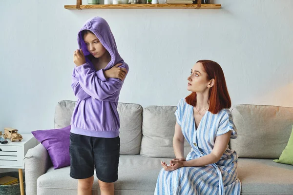 Worried woman talking to offended daughter standing in hood in living room, generation gap — Stock Photo