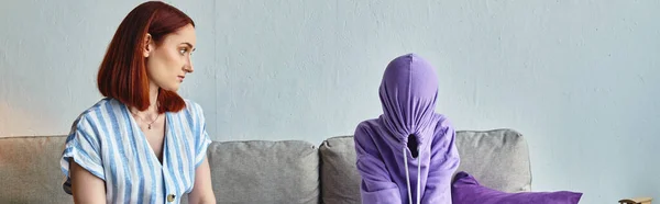 Worried woman talking to upset daughter obscuring face with hood on couch in living room, banner — Stock Photo