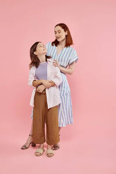 Full length of happy and stylish mother with teenage daughter looking at each other on pink — Stock Photo