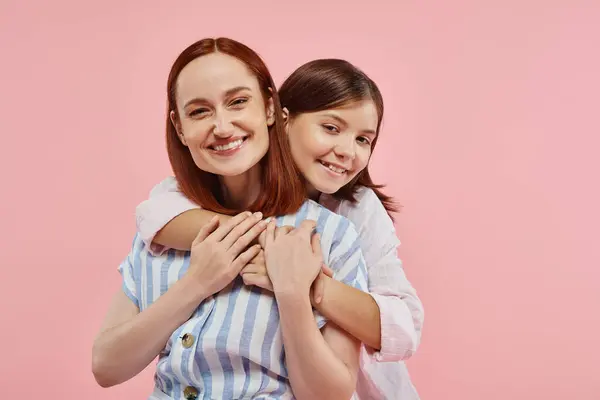 Веселая девочка-подросток, обнимающая стильную маму, улыбающуюся на розовом фоне, единство мамы и дочери — стоковое фото