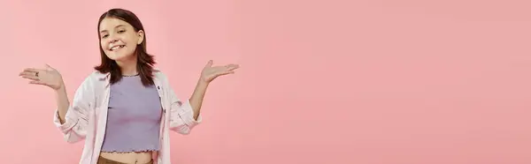 Happy teenage girl in casual attire posing with open arms and looking at camera on pink, banner — Stock Photo