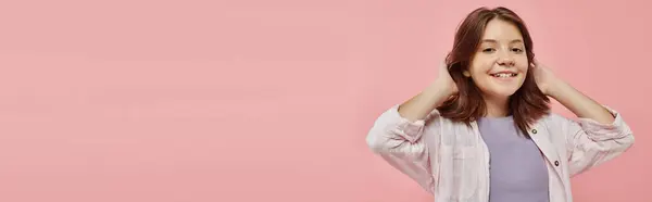 Menina pré-adolescente alegre e elegante com cabelo brilhante saudável sorrindo para a câmera em pano de fundo rosa, banner — Fotografia de Stock