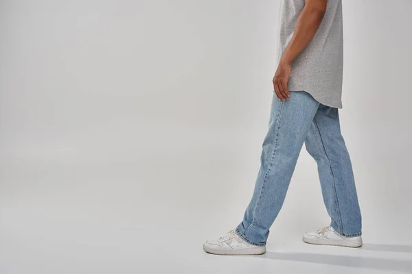 Hombre afroamericano con estilo en jeans casuales de moda y camiseta gris, espacio de copia para la publicidad - foto de stock