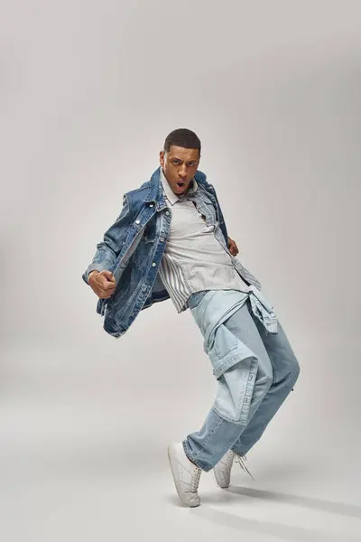 Handsome emotional african american man in denim outfit posing on white backdrop, fashion concept — Stock Photo