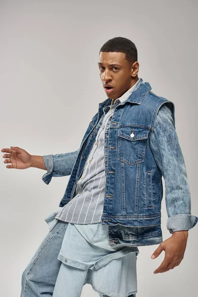 Gut aussehender afrikanisch-amerikanischer Mann in stylischem Jeans-Outfit posiert in Bewegung, Modekonzept — Stockfoto