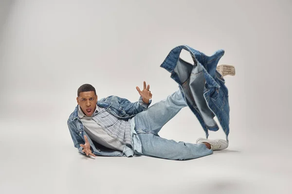 Attraktive emotionale afrikanisch-amerikanische Mann in stilvollem Jeans-Outfit posiert in Bewegung, Modekonzept — Stockfoto