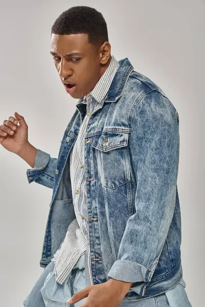 Attractive emotional african american man in stylish denim outfit posing in motion, fashion concept — Stock Photo