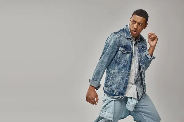 Attractive emotional african american man in stylish denim outfit posing in motion, fashion concept — Stock Photo