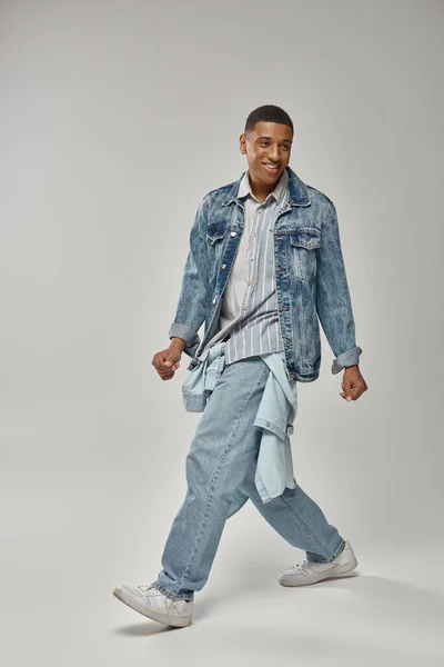 Молодой модный африканский американец в стильной джинсовой одежде позирует на белом фоне, мода — стоковое фото