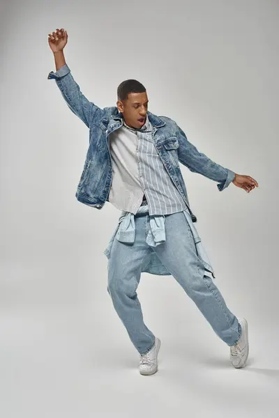 Attrayant homme émotionnel afro-américain en tenue de denim élégant gestuelle vivante, concept de mode — Photo de stock