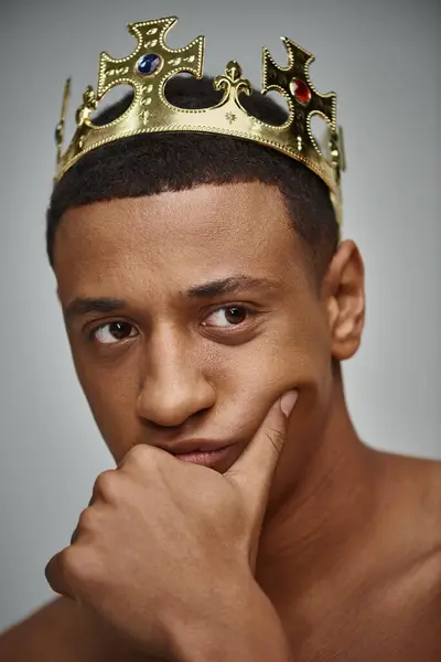 Alluring african american man in golden crown posing topless with hand near face, fashion concept — Stock Photo