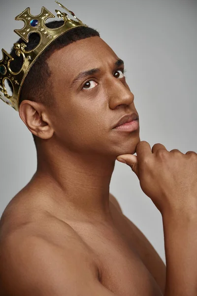 Привабливий афроамериканський чоловік в золотій короні позує топлес з рукою біля обличчя, концепція моди — стокове фото
