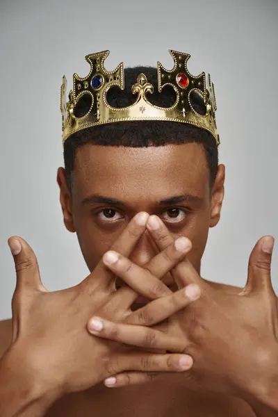 Привабливий афроамериканський чоловік в золотій короні позує топлес з руками біля обличчя, концепція моди — стокове фото