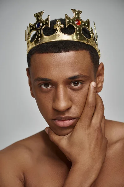 Sedutor homem afro-americano em ouro coroa posando topless com mão perto da cara, conceito de moda — Fotografia de Stock