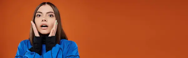 Bannière de femme choquée avec nez percé touchant les joues avec les mains et sur fond orange — Photo de stock