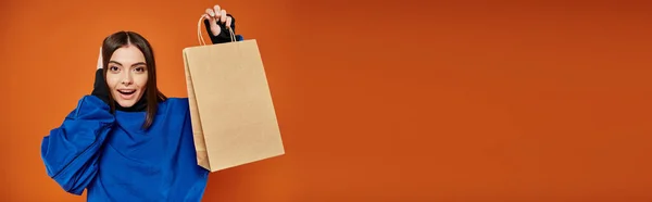 Banner of excited woman in autumn attire holding shopping bag with black friday letters on orange — Stock Photo
