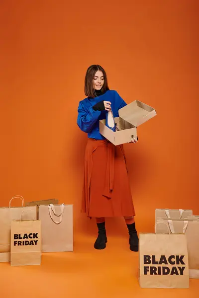 Glückliche Frau hält Karton mit Ballettflaschen in der Hand und steht neben Einkaufstüten, schwarzer Freitag — Stockfoto